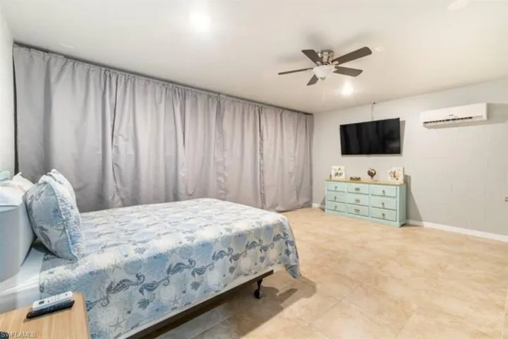 Bedroom with tile patterned flooring, an AC wall unit, and ceiling fan