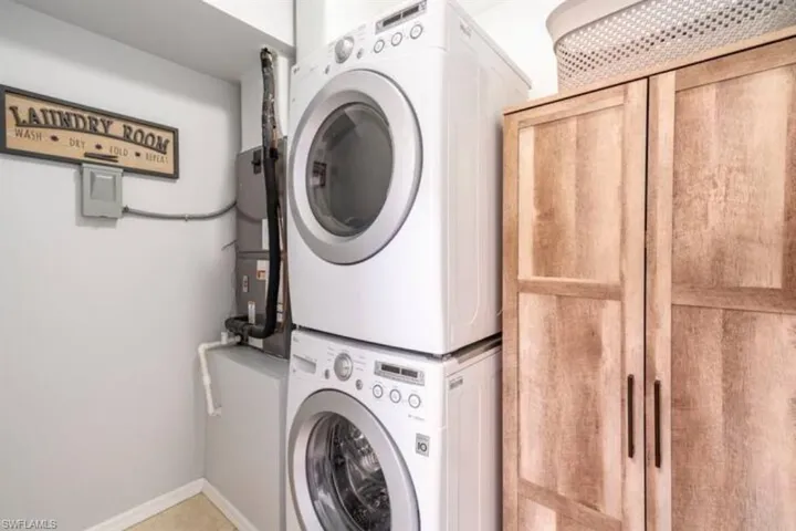Clothes washing area featuring cabinets and stacked washer and dryer