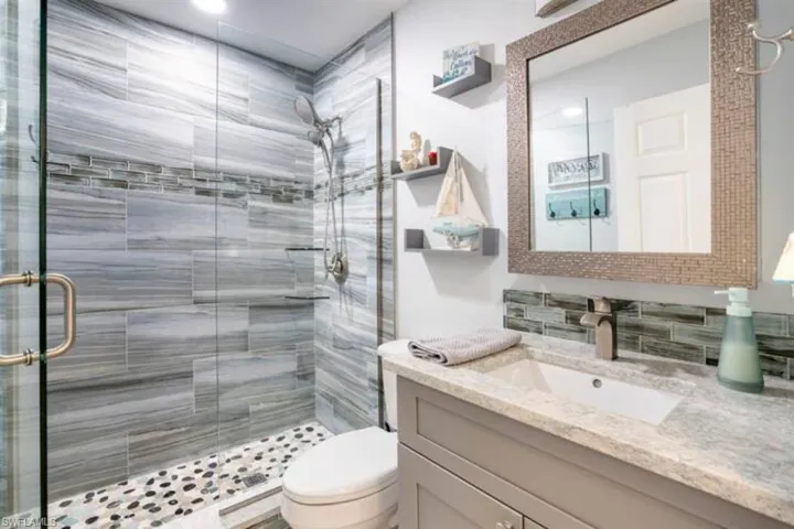 Bathroom featuring a shower with shower door, toilet, and vanity
