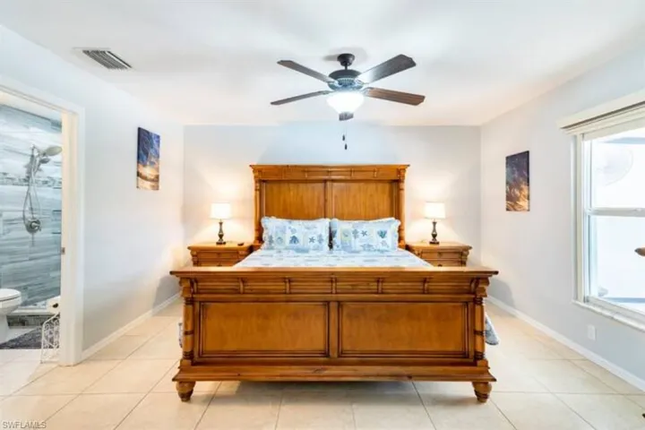 Bedroom with light tile patterned flooring, multiple windows, and ceiling fan