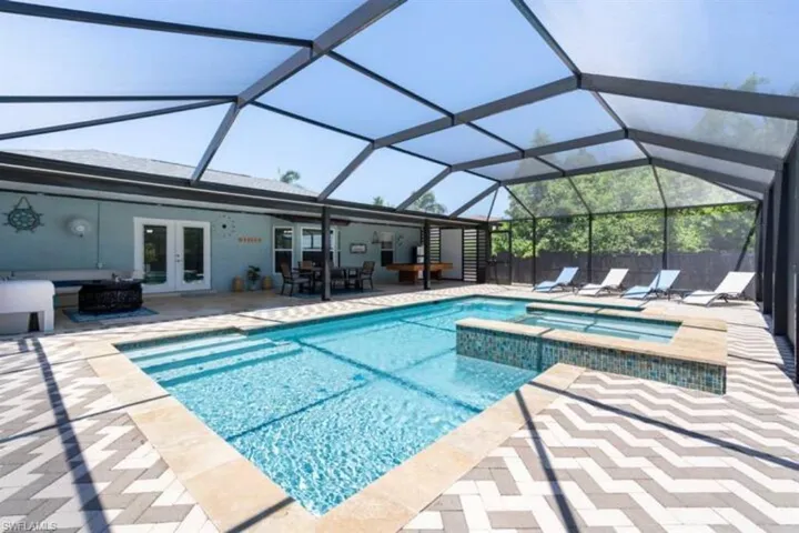 View of pool with a lanai, a patio, an in ground hot tub, and french doors
