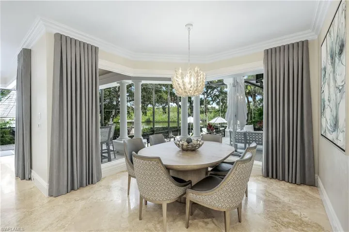 Chic secondary dining space with pool views and custom lighting, ideal for casual or formal meals.