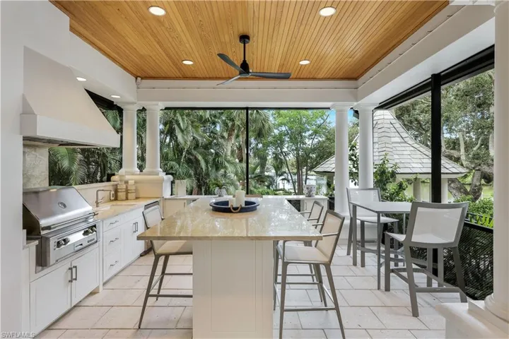 Fully equipped outdoor kitchen with many fine details such as a wood ceiling, white cabinetry, quartz countertops and more!