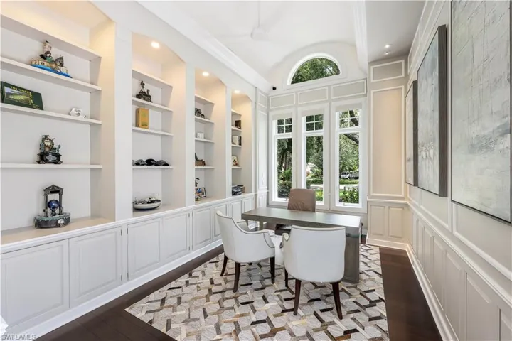 Gorgeous office with built in custom shelving, decorative wood paneling and stunning wood floors.