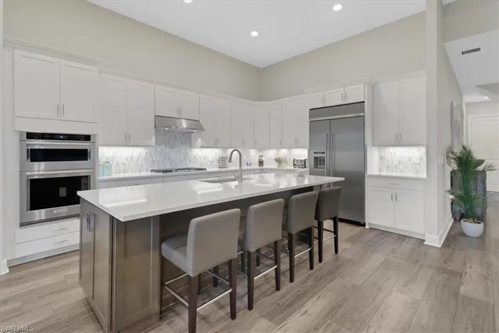 Kitchen featuring appliances with stainless steel finishes, white cabinets, sink, and an island with sink
