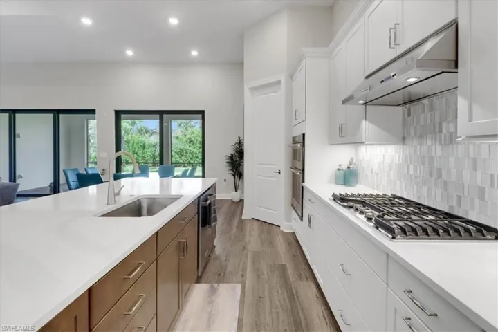 Kitchen featuring backsplash, sink, white cabinetry, appliances with stainless steel finishes, and light hardwood / wood-style floors