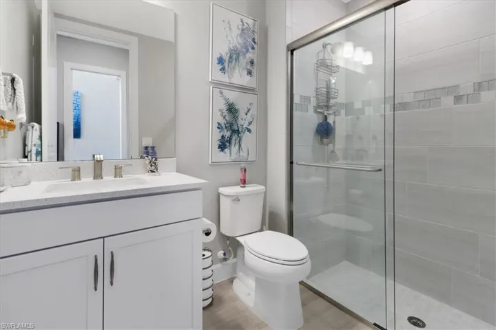 Bathroom with vanity, toilet, and a shower with shower door