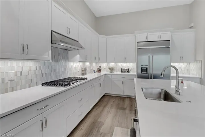 Kitchen with white cabinetry, appliances with stainless steel finishes, sink, and light wood-type flooring