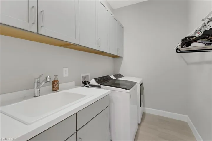 Laundry room featuring cabinets, sink, and washer and clothes dryer