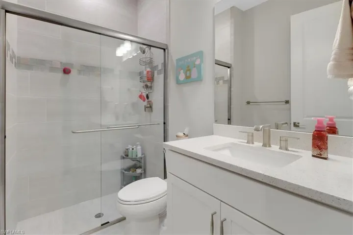 Bathroom featuring vanity, toilet, and an enclosed shower
