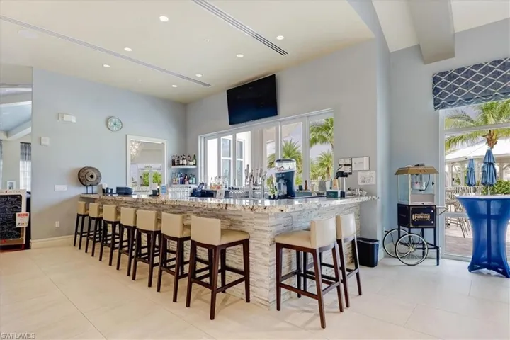 Kitchen featuring a breakfast bar area, light stone counters, a towering ceiling, and kitchen peninsula