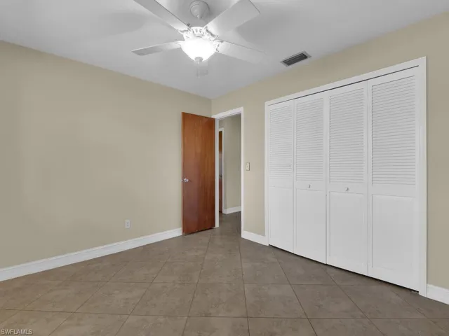 Unfurnished bedroom with ceiling fan, a closet, and tile patterned floors