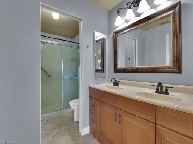 Bathroom featuring double vanity, a shower stall, and light tile patterned floors