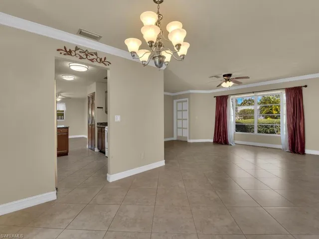 Unfurnished room with a ceiling fan, ornamental molding, hanging lights, and light tile patterned flooring
