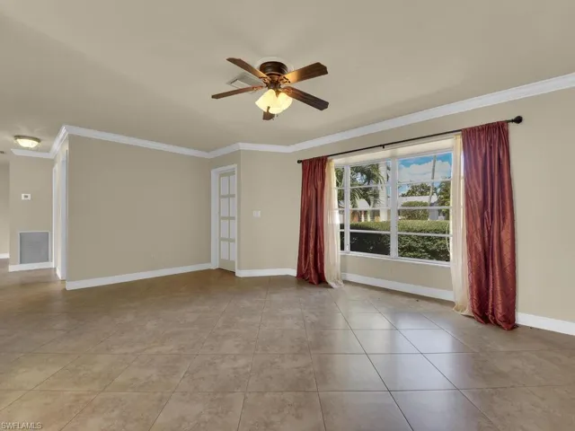 Spare room with a ceiling fan, ornamental molding, and light tile patterned flooring
