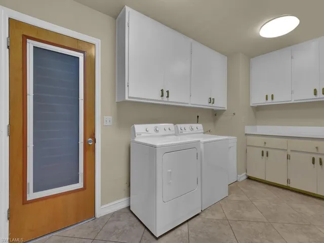 Laundry room featuring cabinet space, washer and dryer, and light tile patterned flooring
