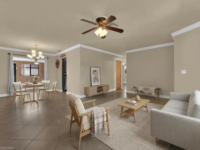 Tiled living area featuring ornamental molding, a chandelier, and a ceiling fan