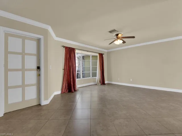 Empty room with crown molding, a ceiling fan, and light tile patterned floors