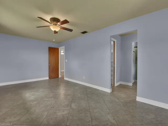Empty room with a ceiling fan and light tile patterned floors