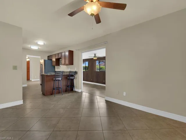 Kitchen with a kitchen bar, a peninsula, light tile patterned flooring, a ceiling fan, and dark wood finish cabinets