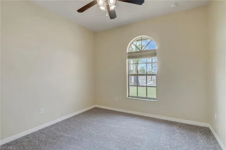 Carpeted spare room featuring ceiling fan