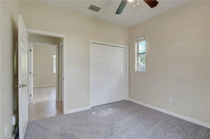Unfurnished bedroom featuring a closet, ceiling fan, and light colored carpet