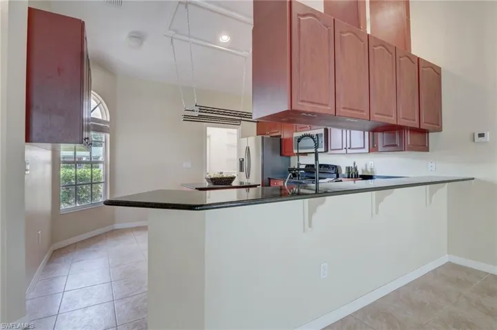 Kitchen with appliances with stainless steel finishes, kitchen peninsula, a breakfast bar area, and light tile patterned floors
