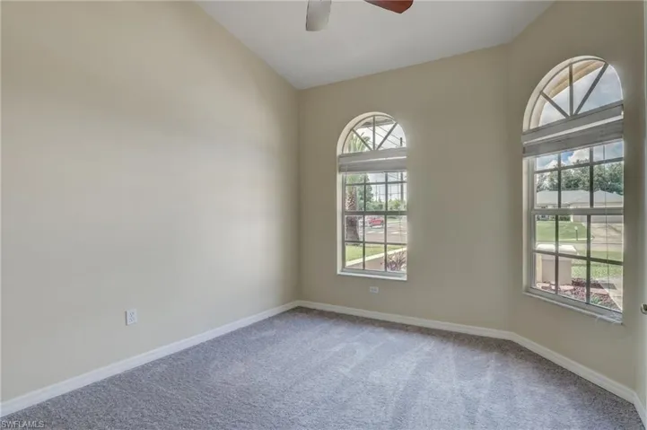 Unfurnished room featuring carpet flooring, lofted ceiling, and ceiling fan