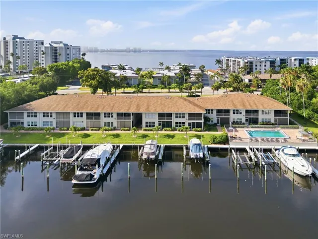 Waterfront condominium complex featuring a private boat dock, outdoor swimming pool, and screened balconies