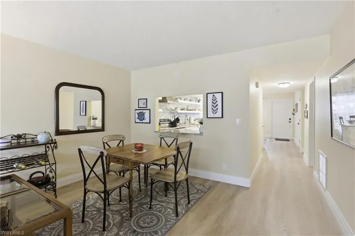 Dining area featuring wood-finish flooring and a pass-through window to the kitchen