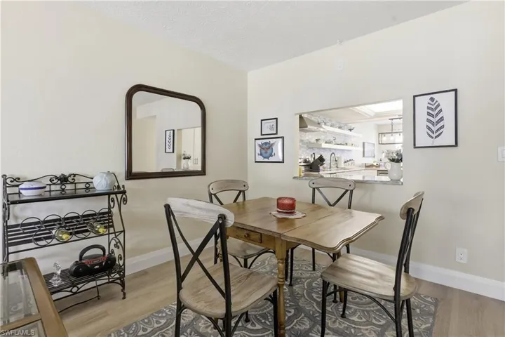 Dining area featuring wood-finish flooring and a kitchen pass-through with a stone countertop