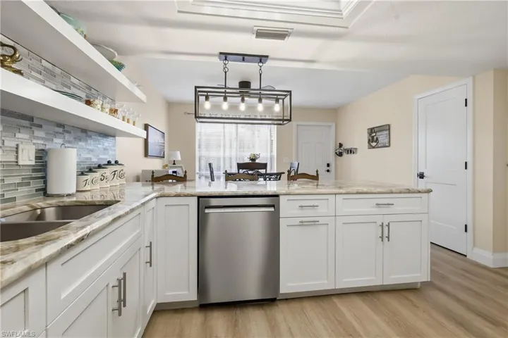 Kitchen featuring white shaker-style cabinetry, granite countertops, a stainless steel undermount sink, and a mosaic tile backsplash