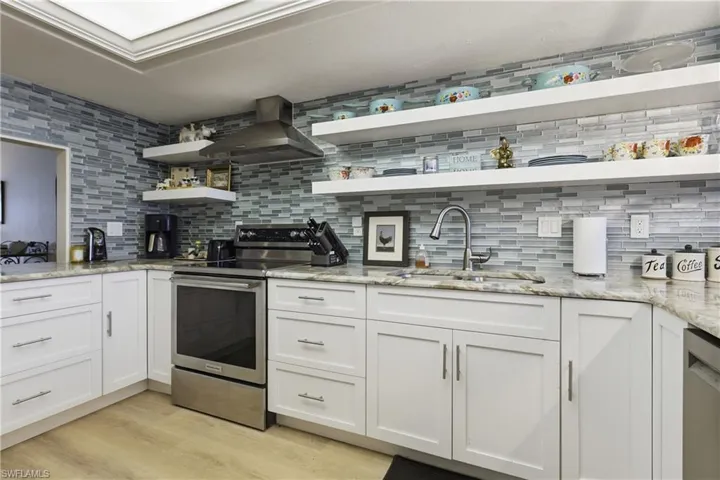 Updated kitchen with white shaker-style cabinetry, granite countertops, and a full-height mosaic tile backsplash