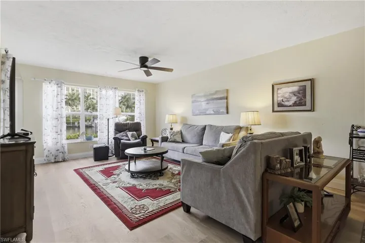 Living area featuring light-toned walls, wood-finish flooring, and multiple windows with waterway views