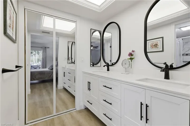 Dual vanity with white cabinetry, matte black hardware, and integrated sinks