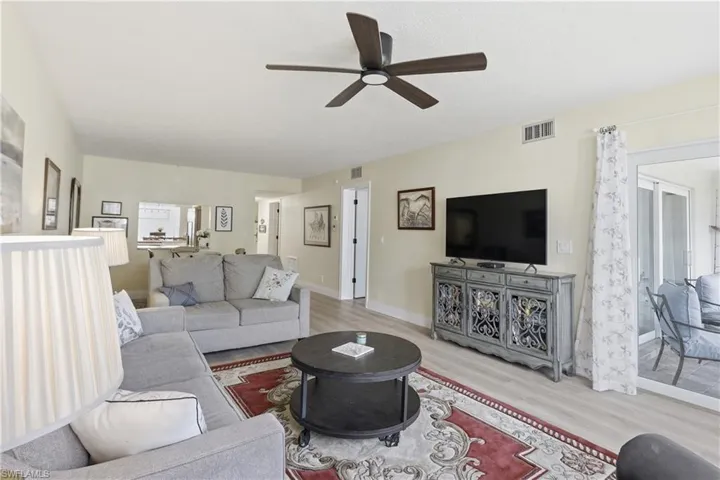 Living room featuring wood-finish flooring, a ceiling fan with dark wood blades, and light-colored walls