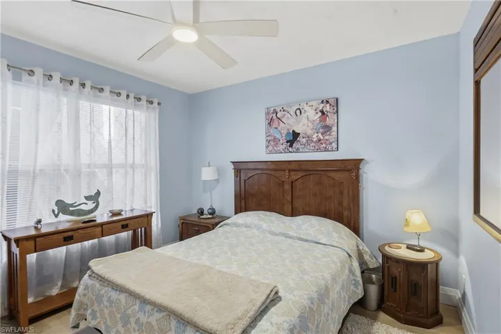 Bedroom featuring a ceiling fan, light blue walls, and a large window with white sheer curtains