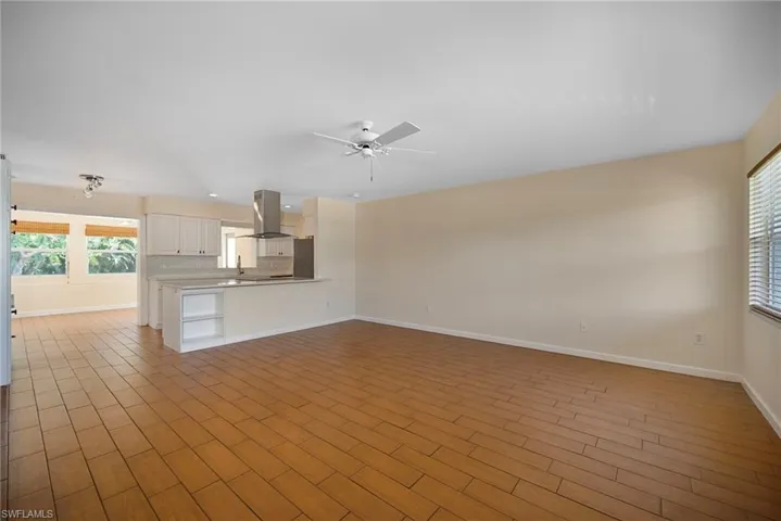 Unfurnished living room featuring dark wood-type flooring and a ceiling fan