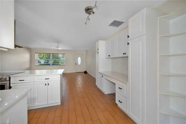 Kitchen with open shelves, white cabinets, built in desk, and stainless steel electric range oven