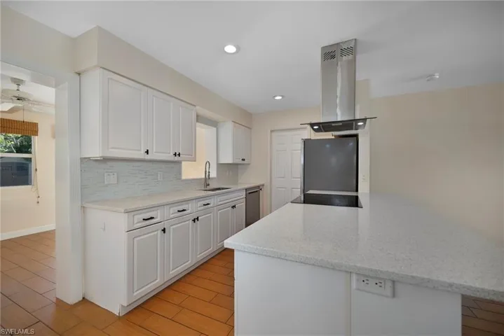 Kitchen with white cabinets, light stone countertops, island range hood, light wood-style floors, and recessed lighting