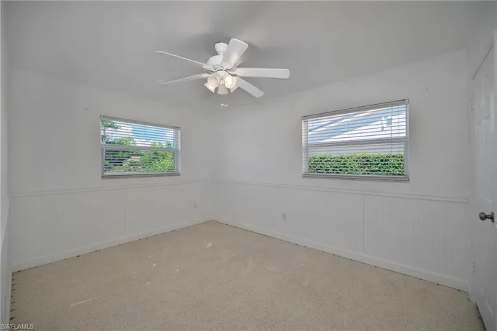 Empty room featuring a wainscoted wall, plenty of natural light, and ceiling fan