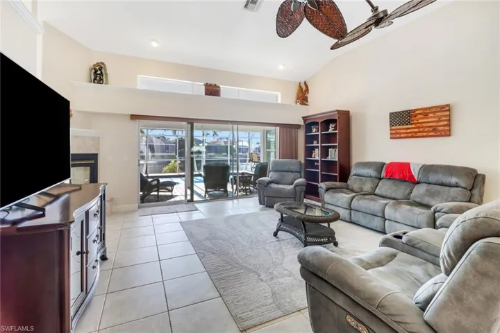 Living room with a tile fireplace, light tile patterned floors, high vaulted ceiling, and ceiling fan