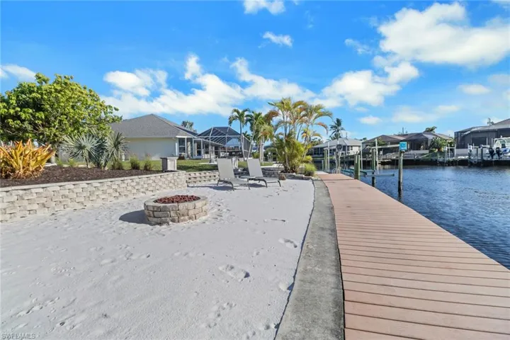 Dock area featuring a water view and an outdoor fire pit