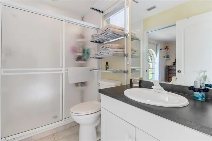 Bathroom featuring tile patterned flooring, vanity, toilet, and walk in shower