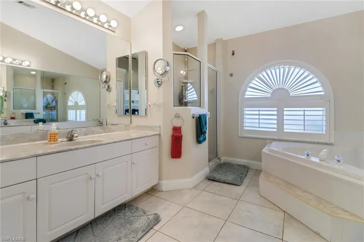 Bathroom with tile patterned floors, a healthy amount of sunlight, independent shower and bath, and vaulted ceiling