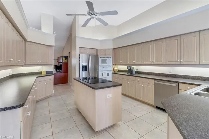 Kitchen with a kitchen island, light tile patterned floors, stainless steel appliances, and high vaulted ceiling