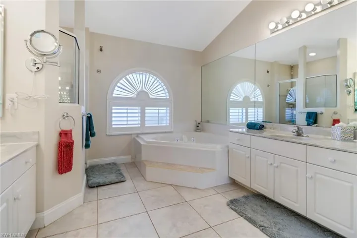 Bathroom with tile patterned floors, a wealth of natural light, lofted ceiling, and shower with separate bathtub