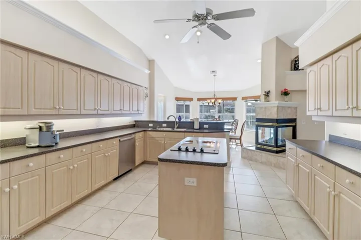 Kitchen with a center island, sink, hanging light fixtures, vaulted ceiling, and light tile patterned floors