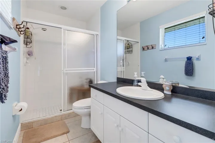 Bathroom featuring toilet, vanity, tile patterned floors, and an enclosed shower