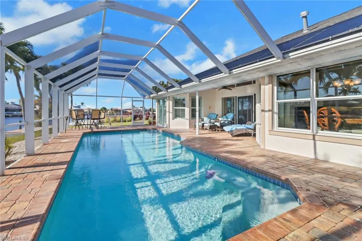 View of swimming pool featuring glass enclosure, ceiling fan, and a patio area